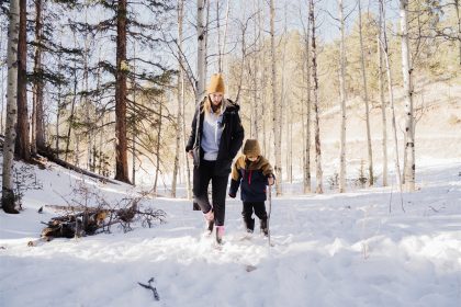 A mother is walking in the snow with her child, wearing HISEA boots.