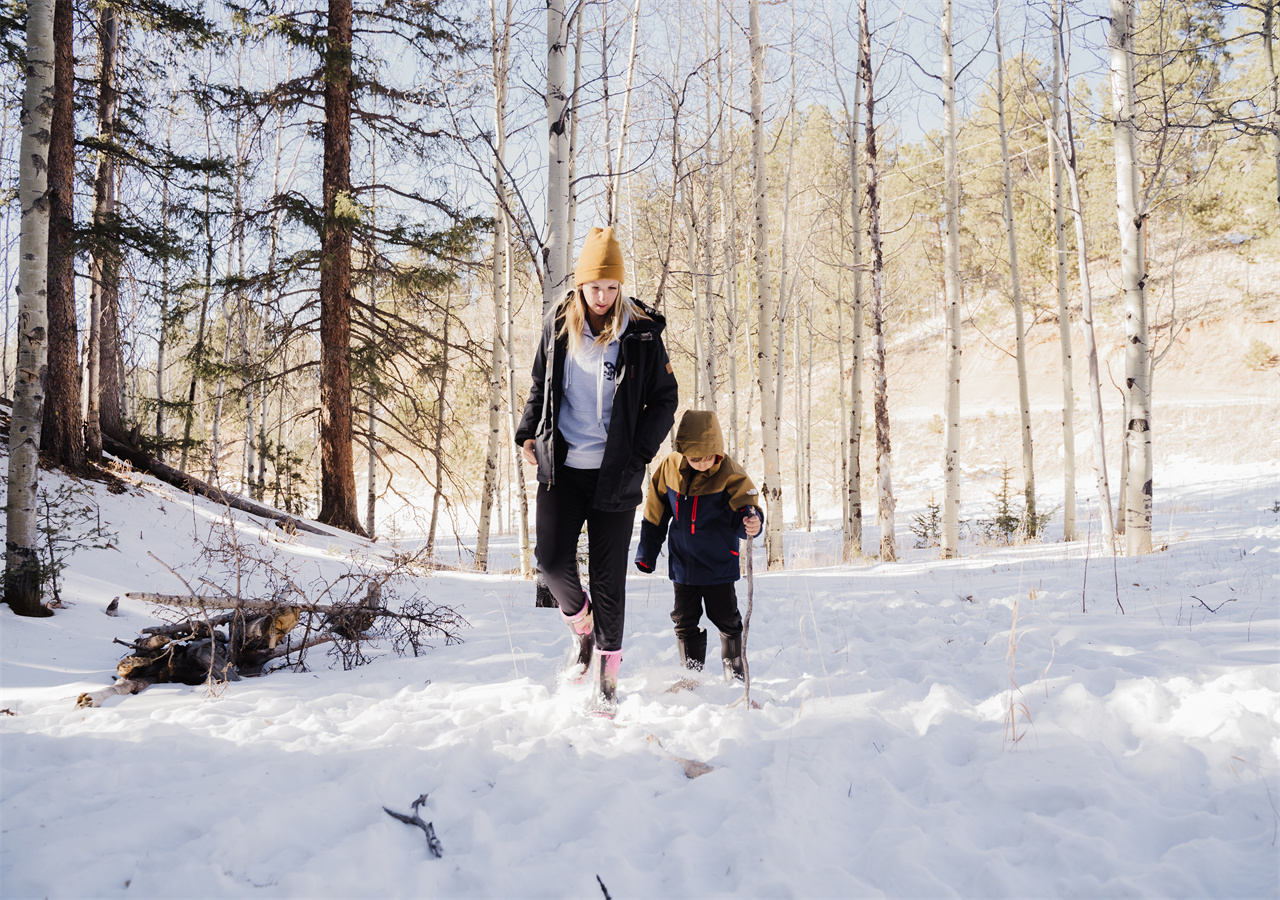 A mother is walking in the snow with her child, wearing HISEA boots.
