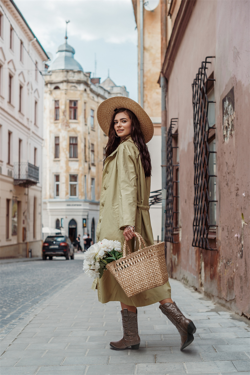 An elegant woman is carrying a handbag with some beautiful flowers inside and is wearing HISEA cowboy boots.